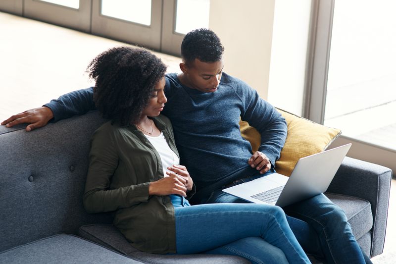 Young couple sitting on their sofa and looking at mortgage rates on a laptop