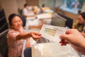 Someone handing a woman an IRS check sealed in an envelope. 