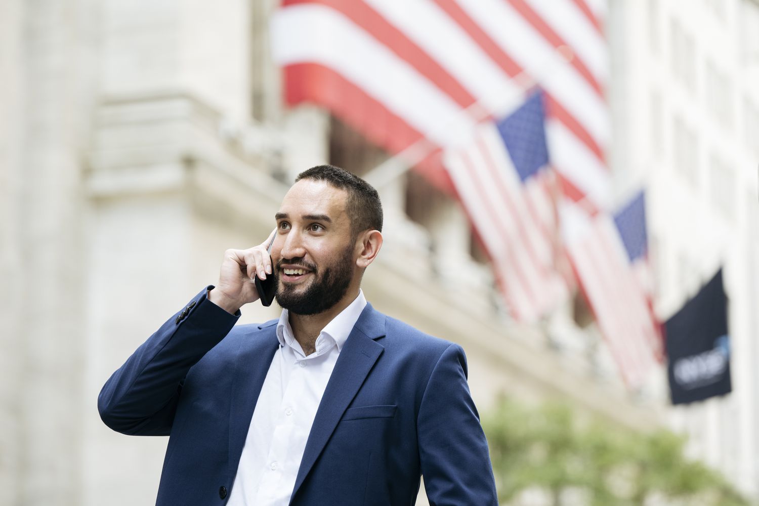 Smiling Wall Street worker on phone outdoors 
