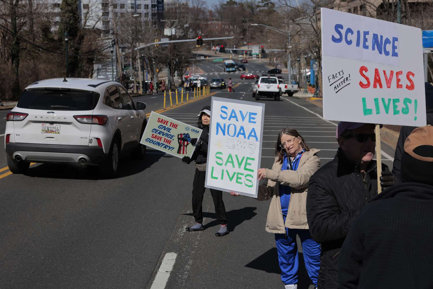Demonstrators protest against Department of Government Efficiency (DOGE) cuts as they wade into traffic along Maryland Route 410 outside the headquarters of the National Oceanic and Atmospheric Administration on March 03, 2025 in Silver Spring, Maryland.