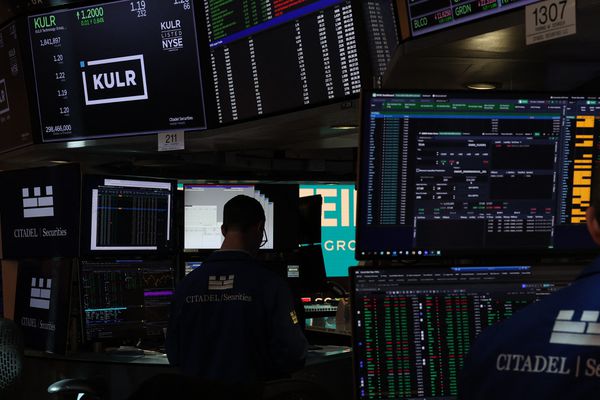 Traders working on a busy stock exchange floor surrounded by numerous monitors displaying financial data and stock information
