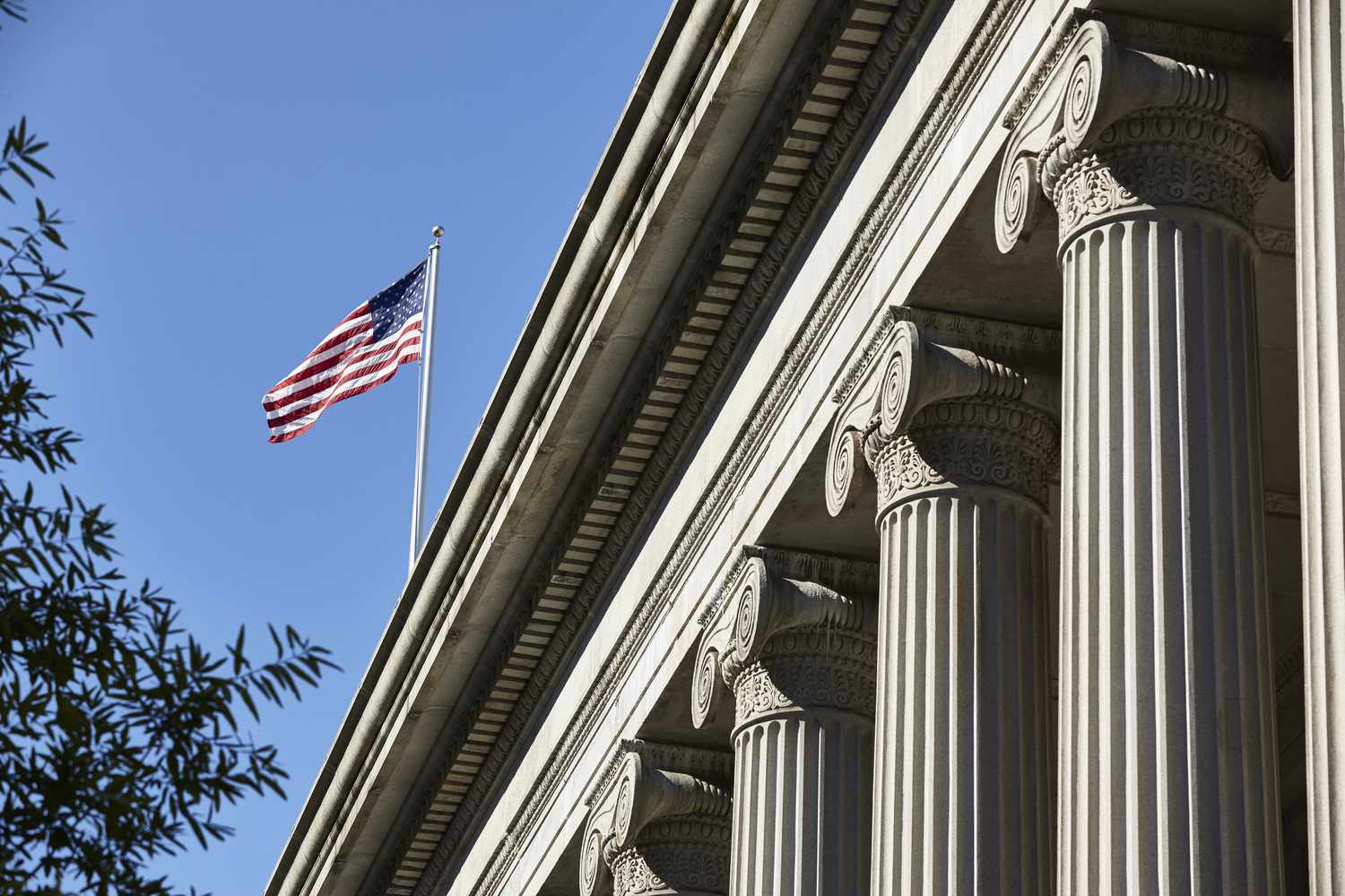 U.S. flag flying over the Treasury Department building, which is in a neoclassical design