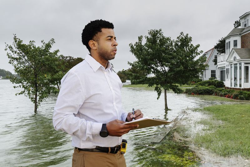 Insurance adjuster examining flooding damage to house