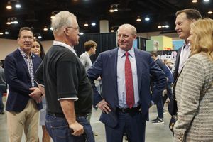 Greg Abel is pictured at the center of a group of people conversing in an indoor event space