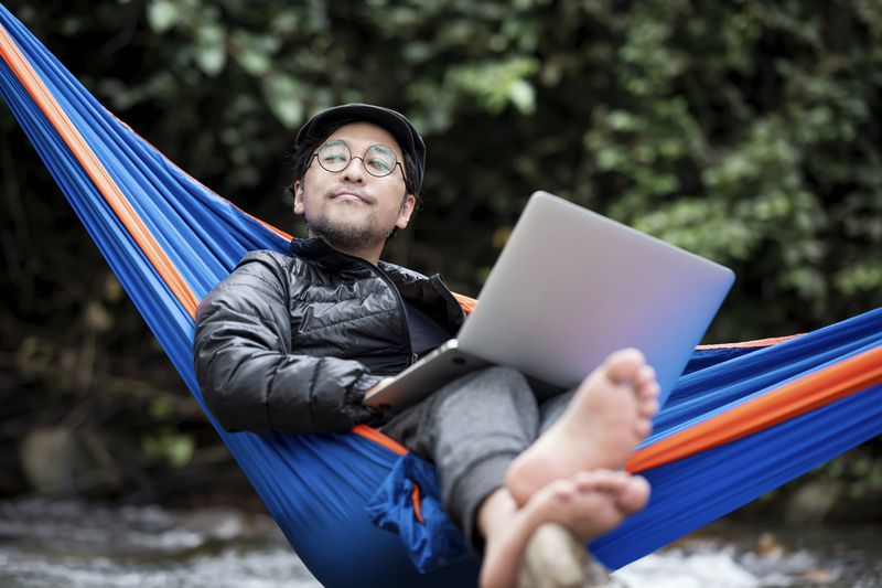A man leisurely checks his insurance face value on his laptop.
