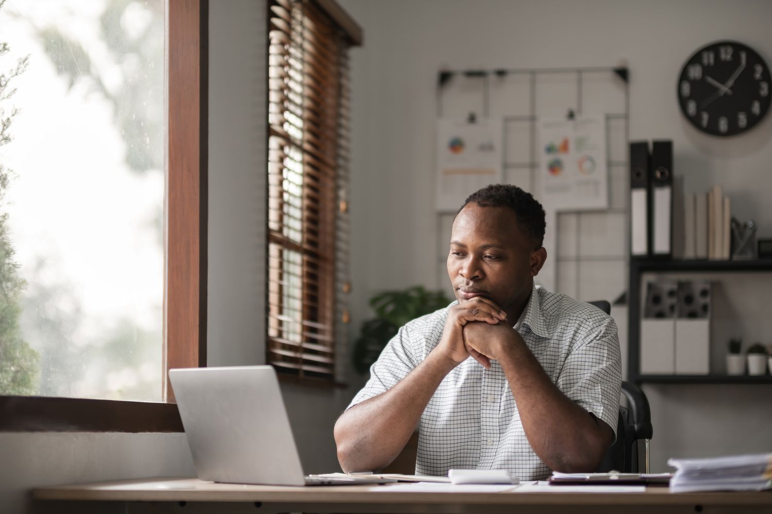 A seated businessman reviews something on a laptop screen