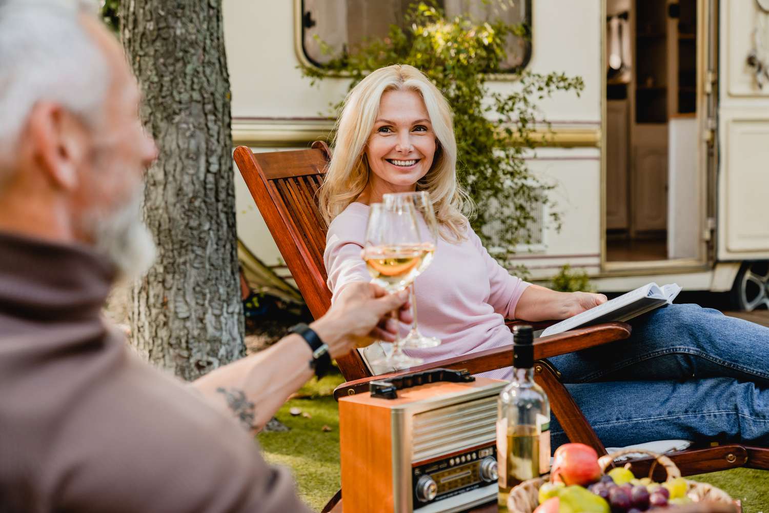 Senior married caucasian couple toasting with glasses of wine with their motor home behind