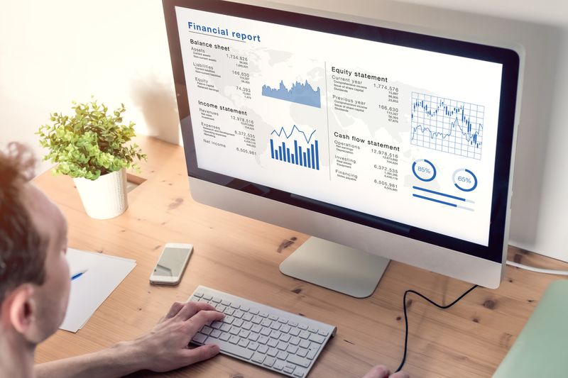 man looking at financial statements on his desktop monitor in a home office