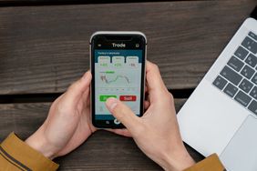 Above angle view of a young man using a trading app