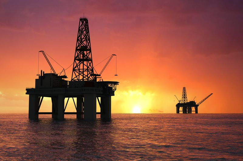 Oil rig in the ocean at sunset