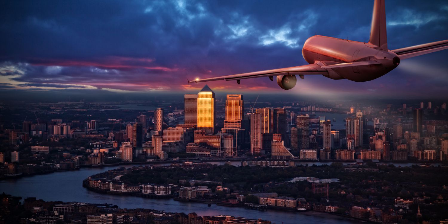 A commercial airplane jetliner flying above business district of London.