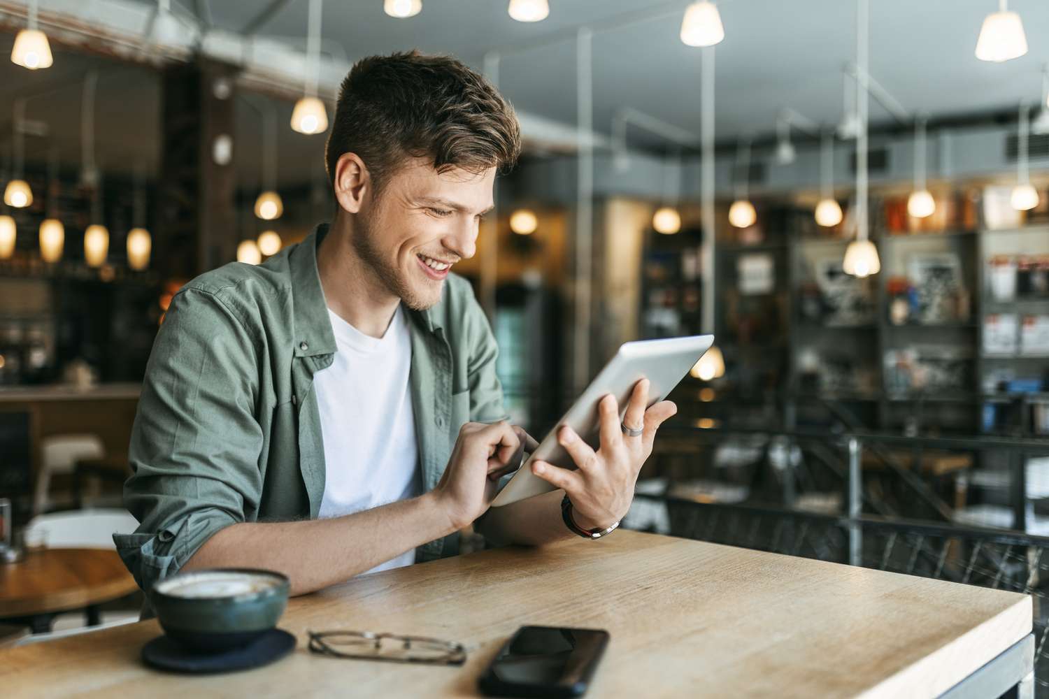Young man reading a tablet in a bookstore or library. 