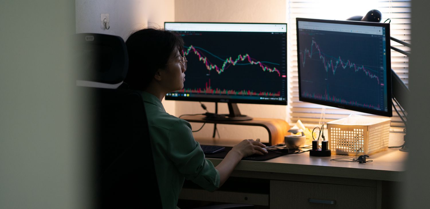Asian stock trader looking at the price cycles on stock charts to come up with strategies for upcoming phases.