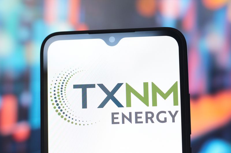 The TXNM Energy logo is seen displayed on a smartphone screen