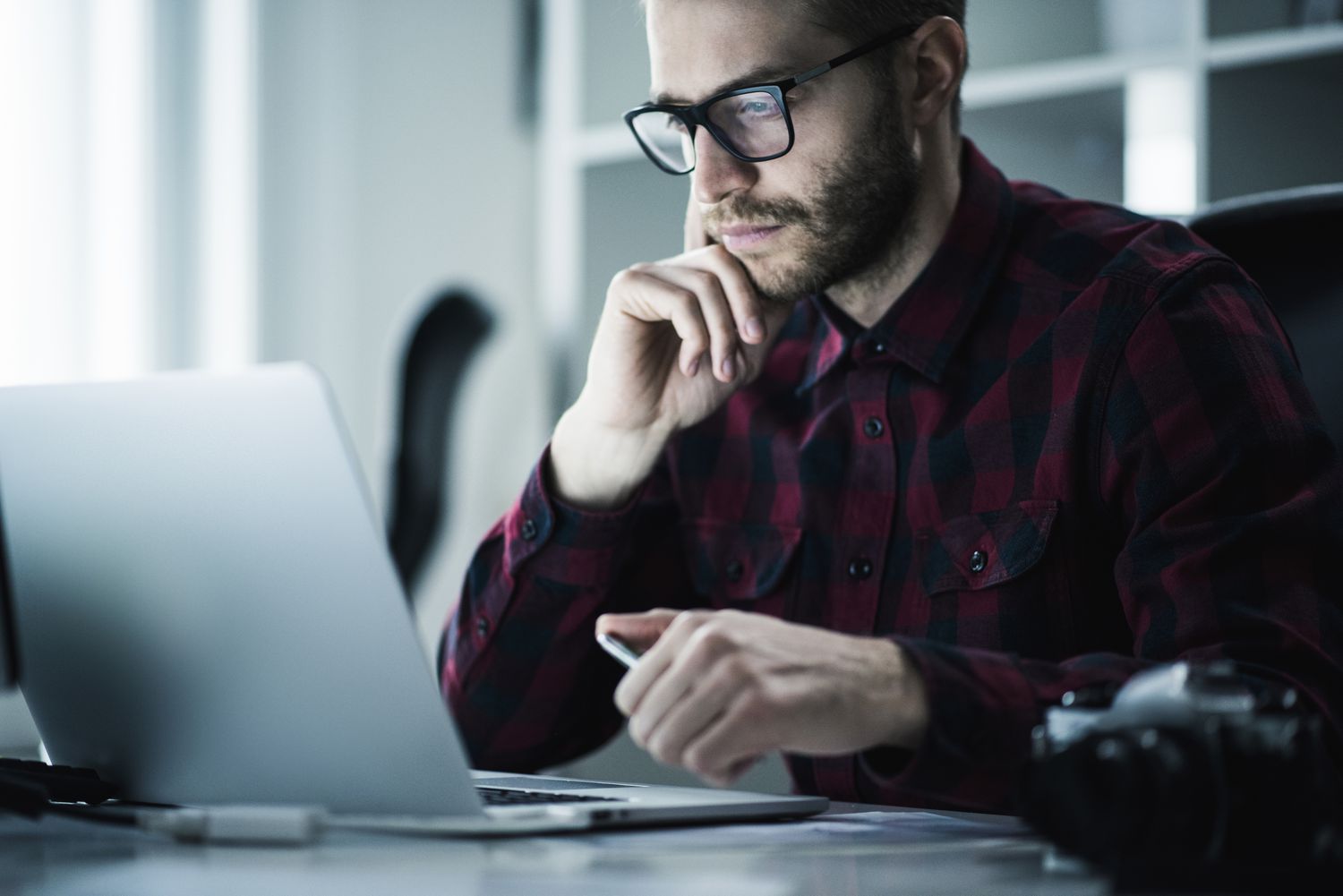 A young man looks at a laptop in a modern office.