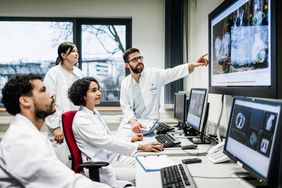 Team of Doctors Look at Lab Results Together on Monitors