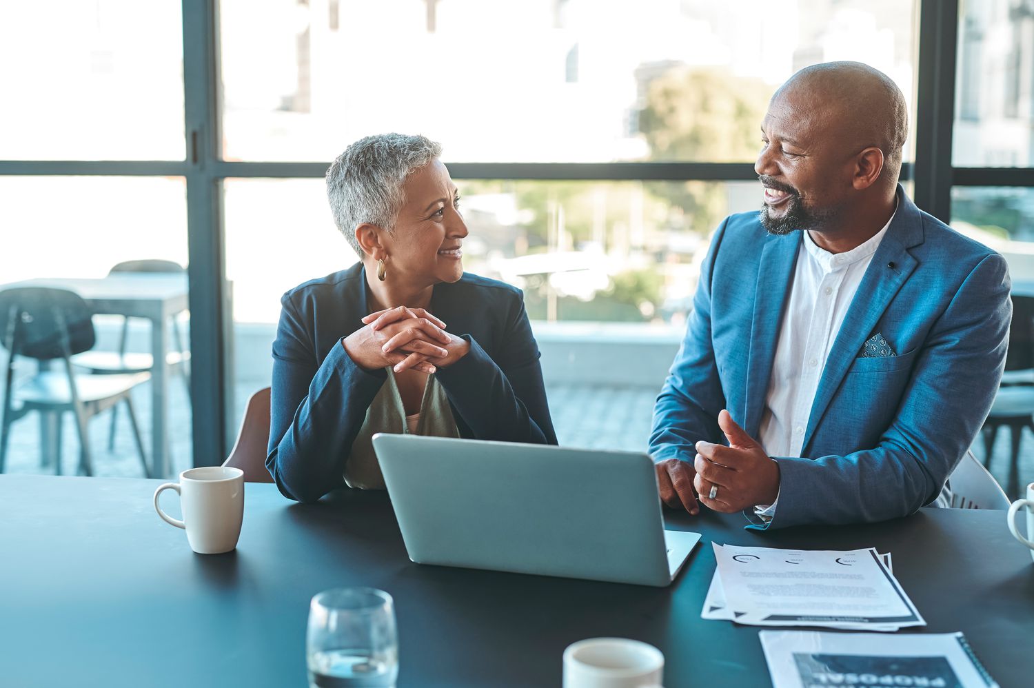 Colleagues talk next to a laptop