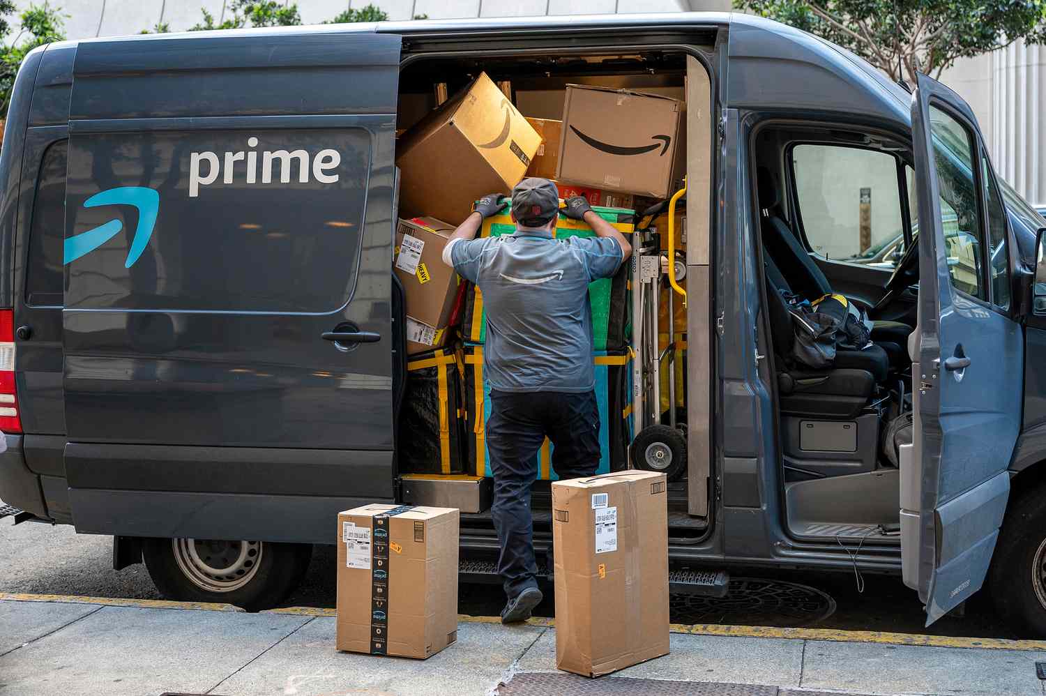 A worker leans into an Amazon Prime van filled with boxes, while delivering packages on Cyber Monday.