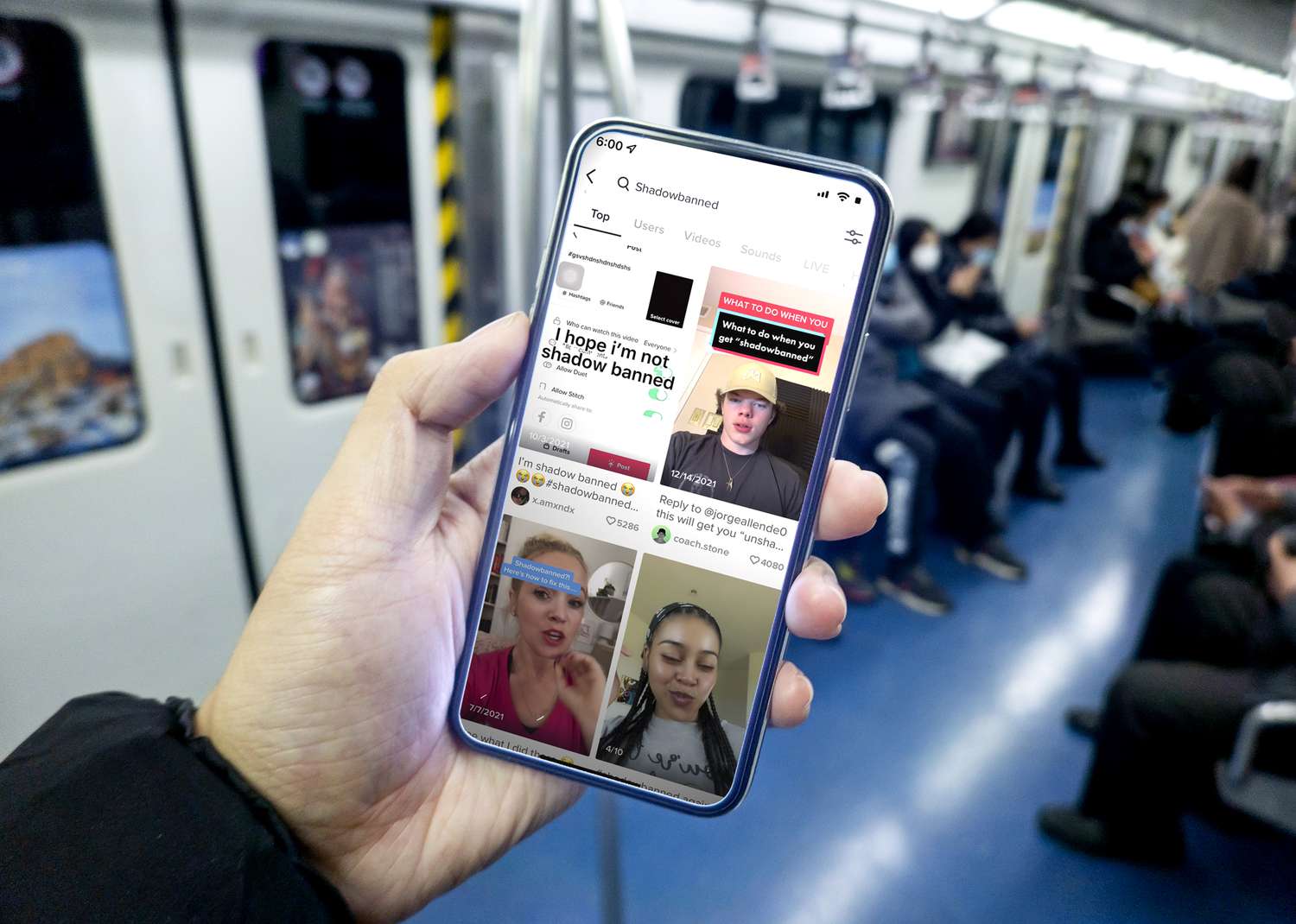 An iPhone with the TikTok app running on it being held by a hand on the subway.
