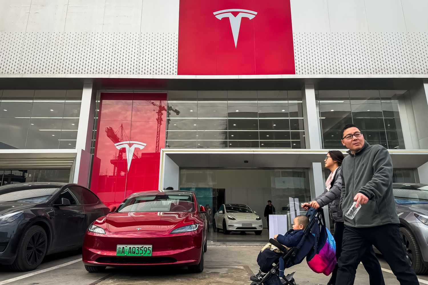 A family walks in front of a Tesla showroom in Chongqing, China. 