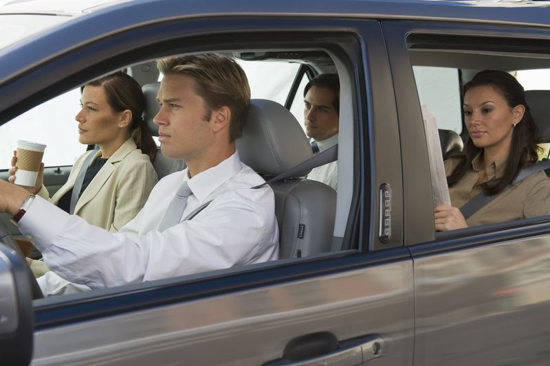 Young man driving car with passengers.