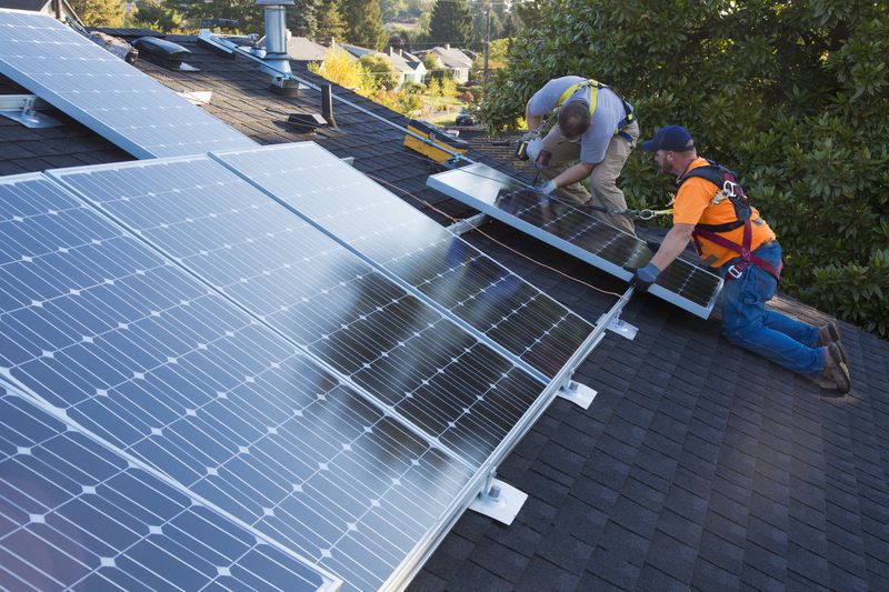 Two men installing solar panels on a residential roof