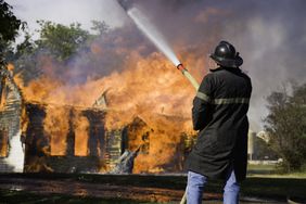 A firefighter hoses down a house fire.