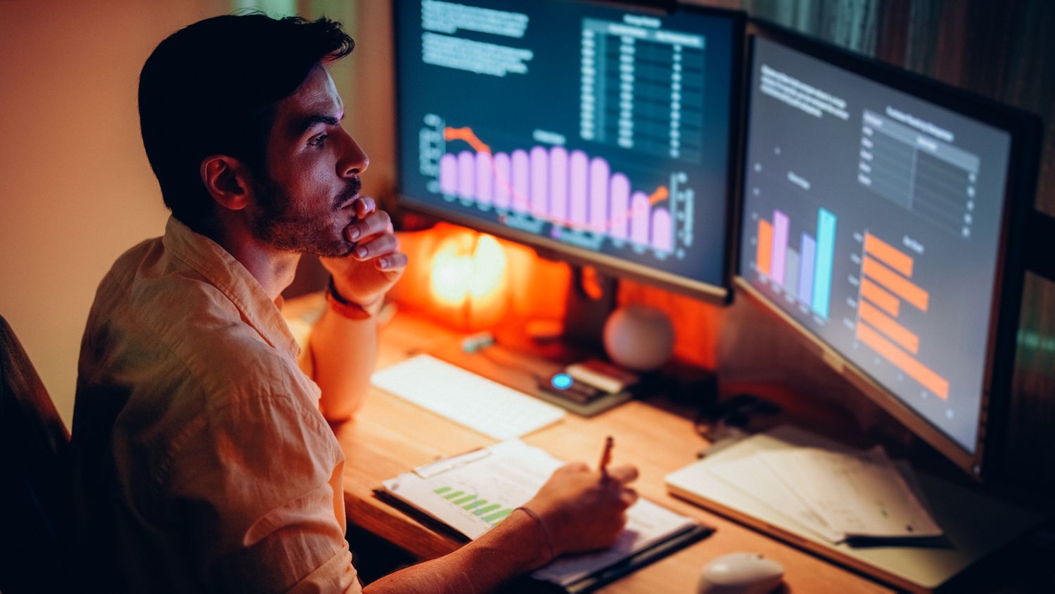 A person at a desk with two screens trading stocks overnight.