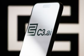 The logo of C3.ai is displayed on a smartphone screen, with the company's geometric black-and-white branding visible in the background