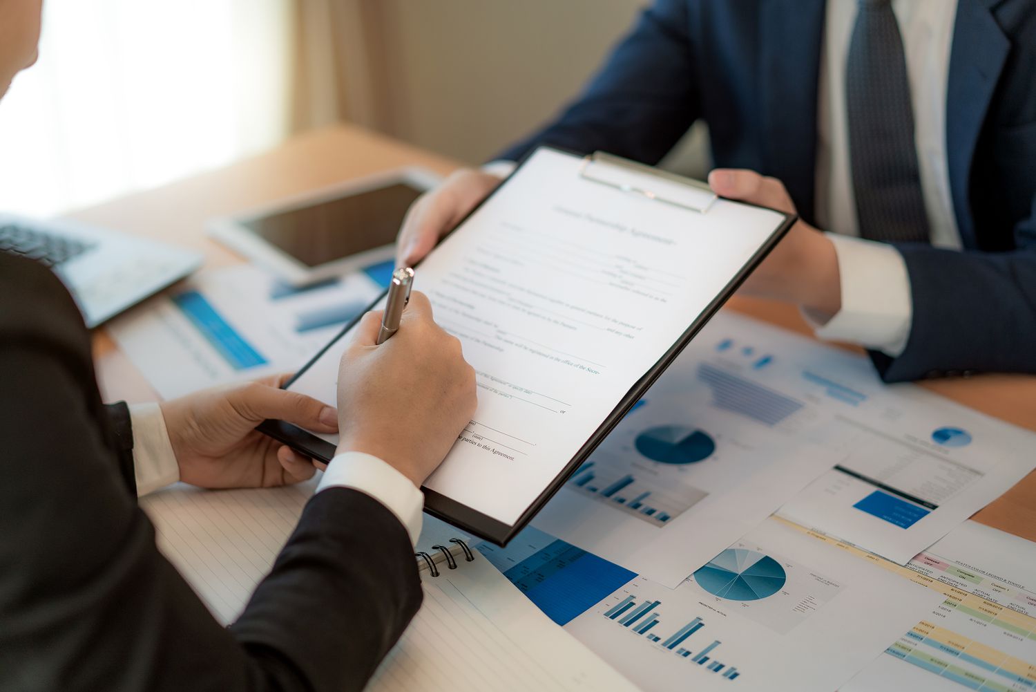 entrepreneur and his business partner signing important business insurance in office