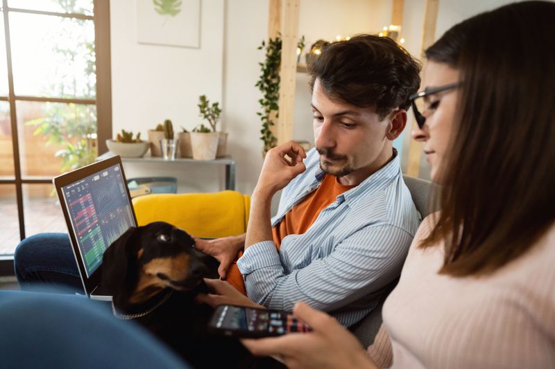 A stressed couple using a laptop and cell phone look at losses they experienced by investing in penny stocks.
