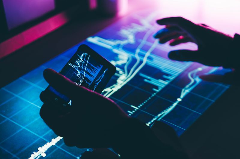 A person holds a smart phone with stock data