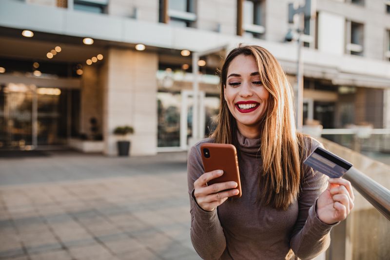 Woman paying with a credit card on her phone outside of a building