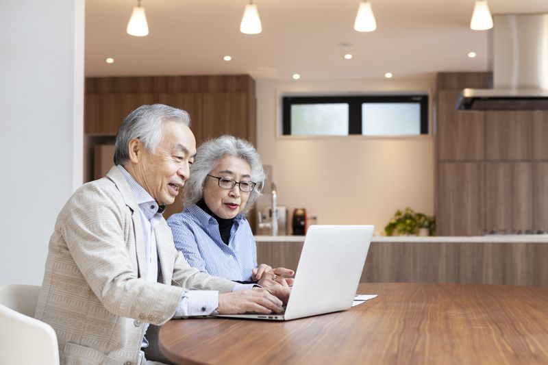 Older couple sitting at their dining table and looking at mortgage rates on a laptop