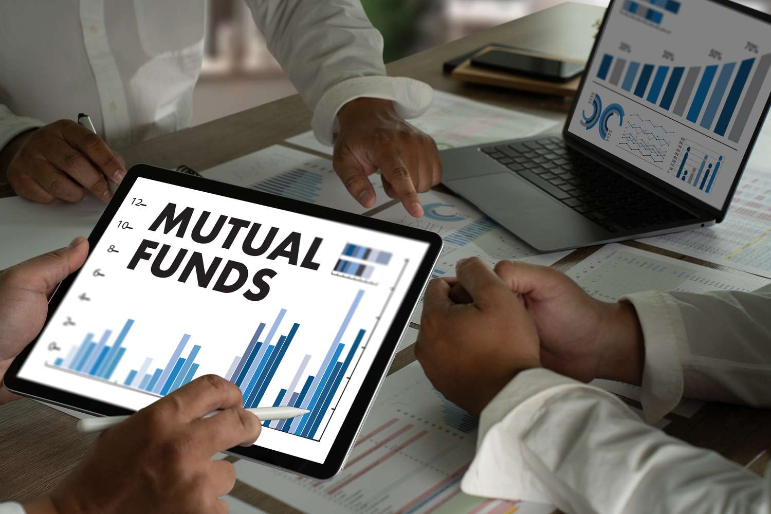 Tablets chowing mutual funds letters, three sets of hands around a table. 