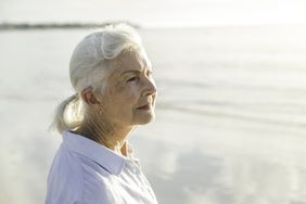 Woman on a beach looks into the distance. 