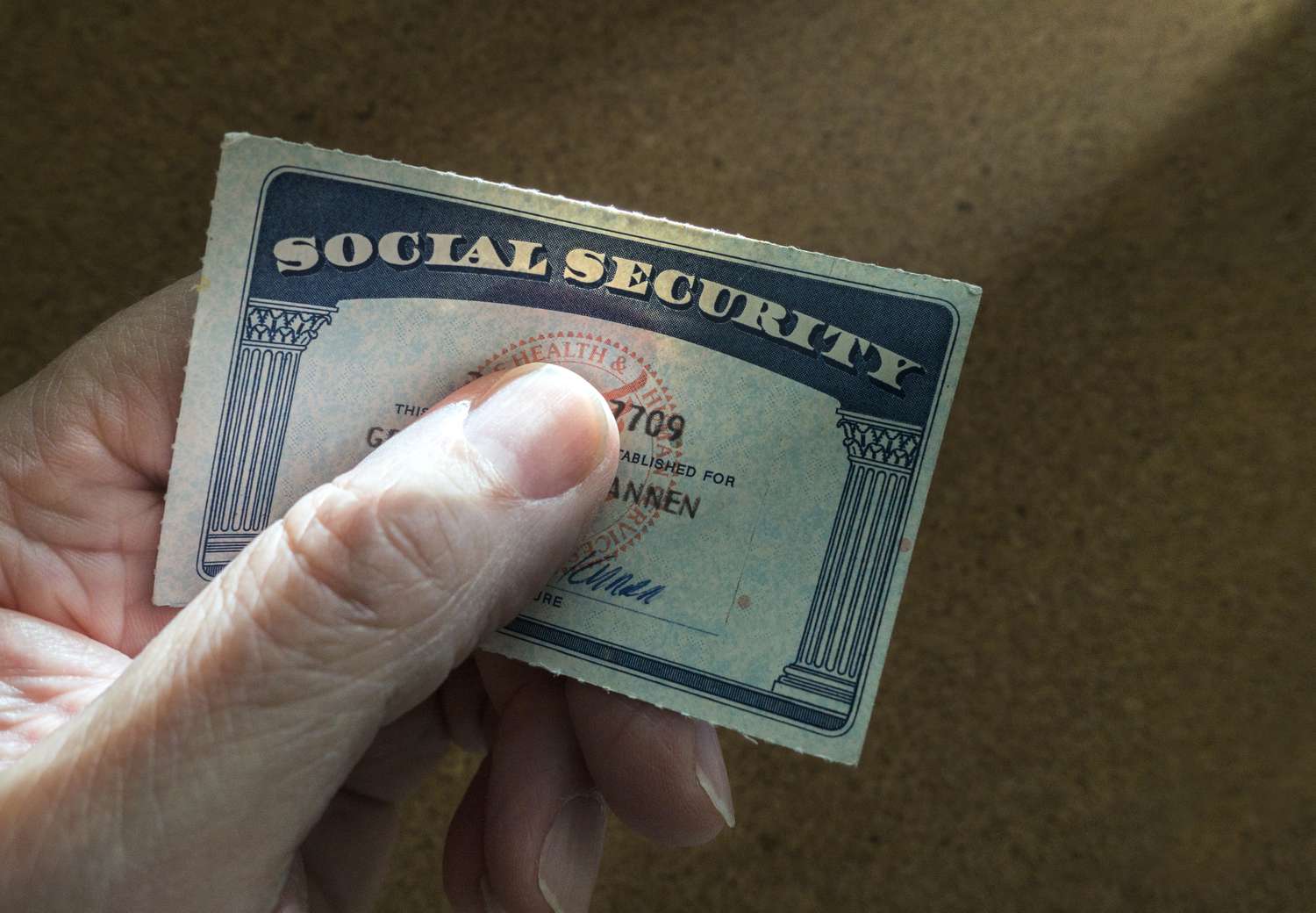 A hand holding a Social Security card