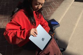 A woman stashes an Apple MacBook in her bag. 