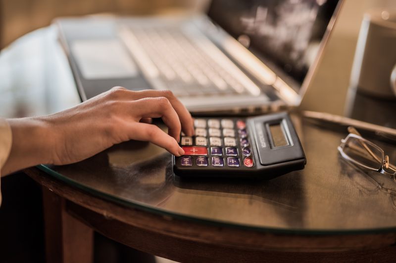 A close-up of young woman using a calculator.