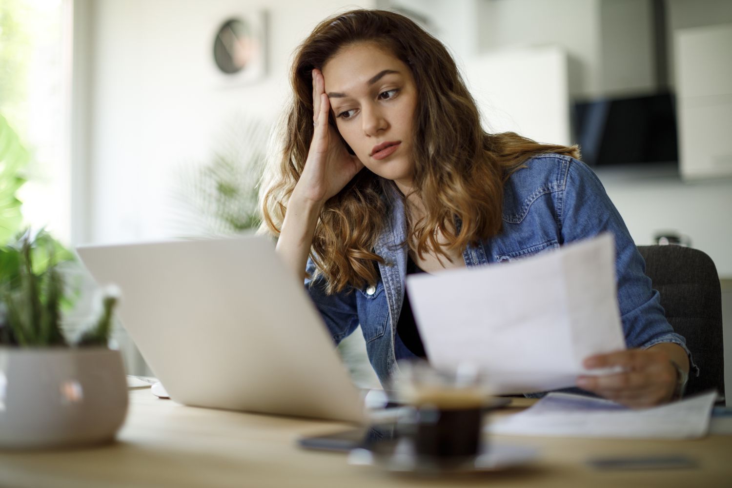 A woman is stressed at a desk with paperwork.