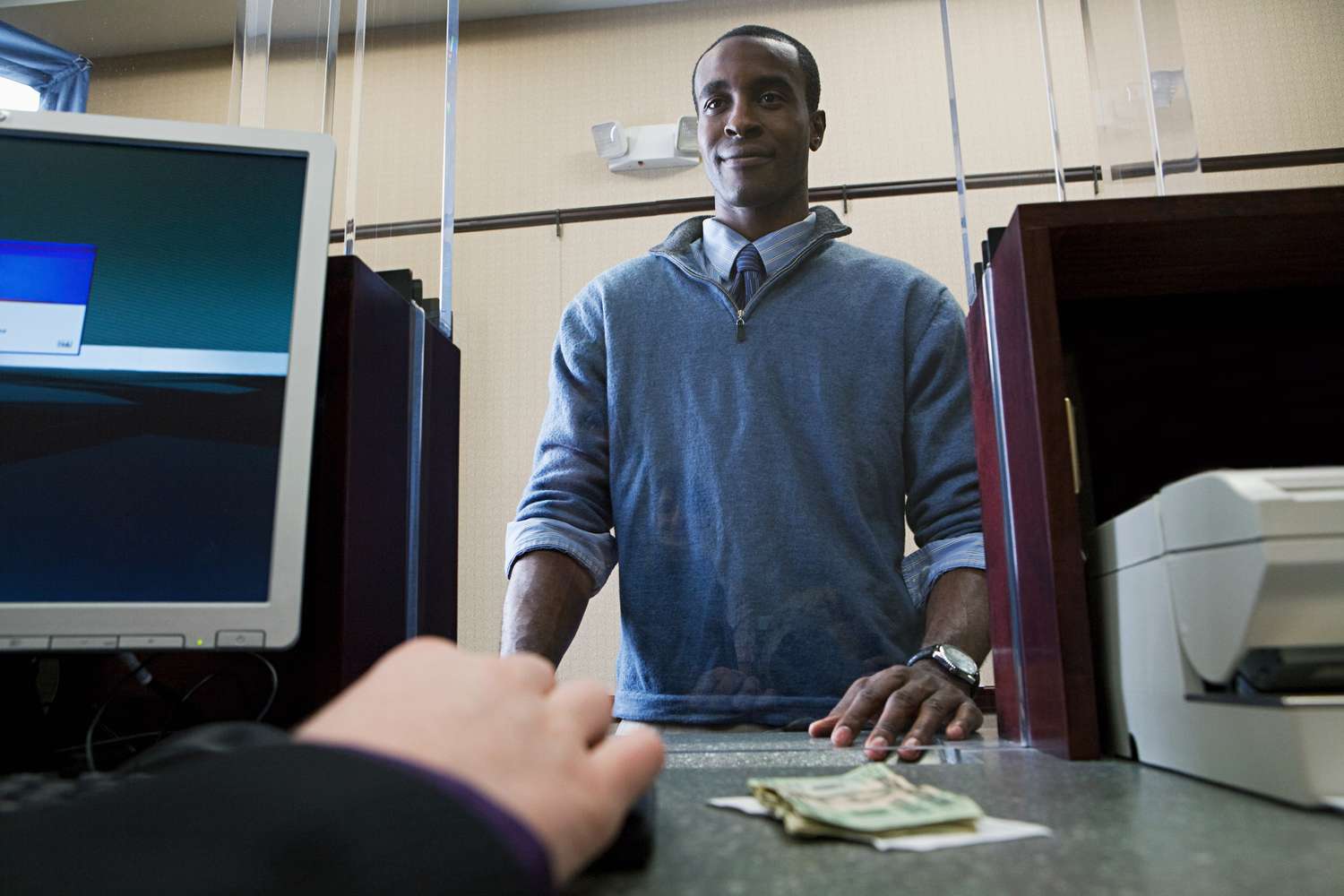 Man stands at bank teller paying for a money order with cash