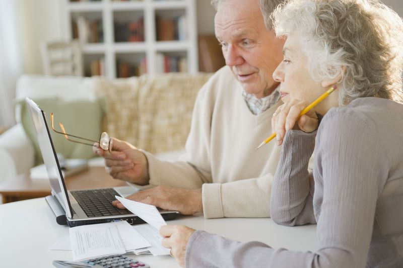 Two people seated at a table, looking at a laptop screen