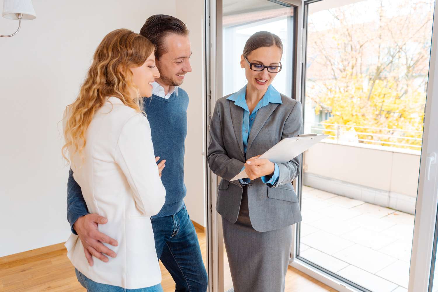 A rental agent discussion lease terms and the termination date with renters in an empty apartment.
