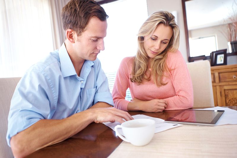 Couple in their 30s sitting in their dining room and looking at mortgage documents and a tablet