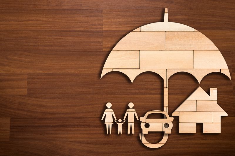 Wooden silhouette of a family under an umbrella as a concept of insurance