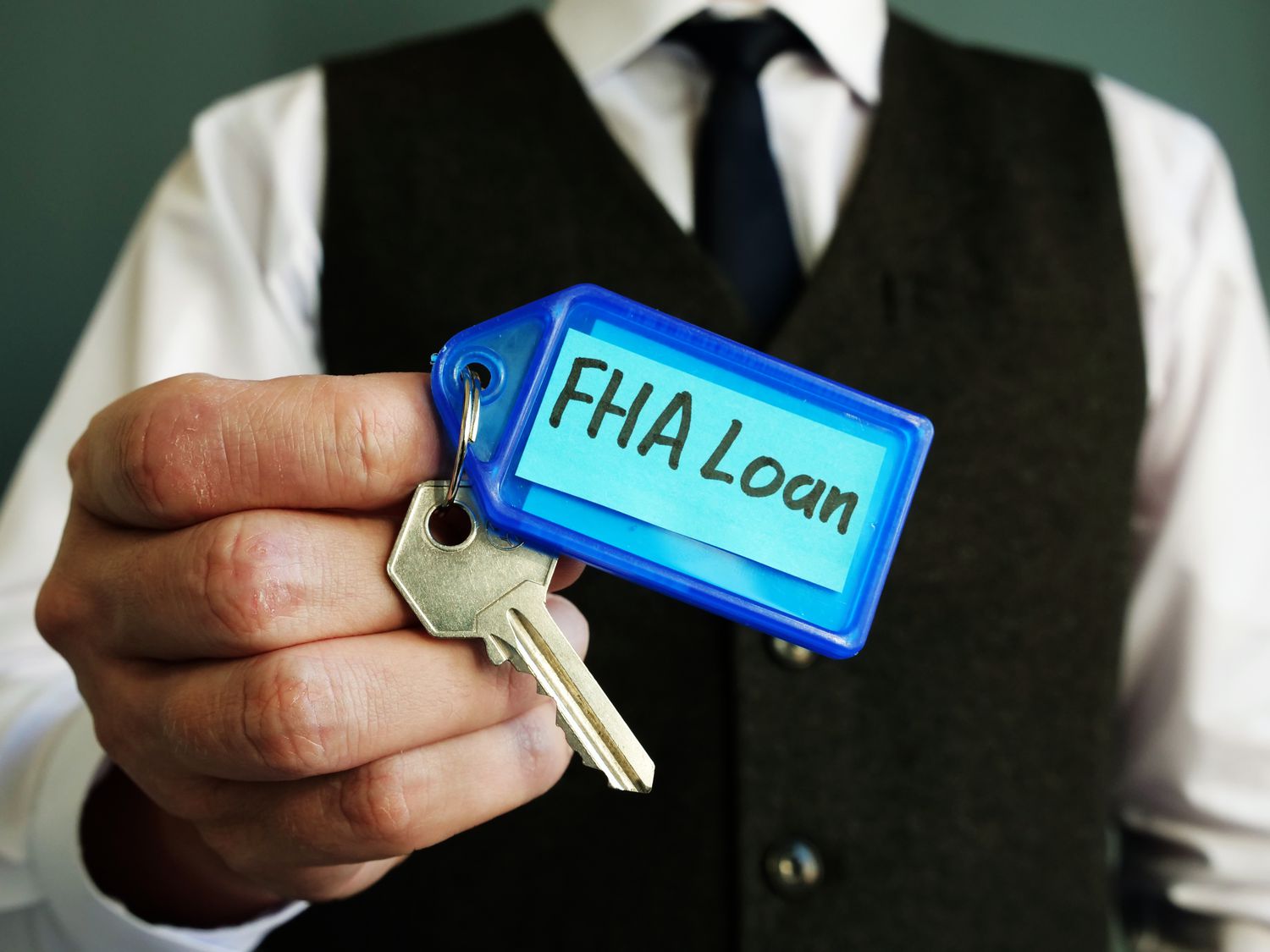 The key with FHA loan sign is in a person's hands.