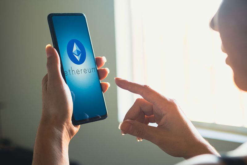 A person holds a phone with the Ethereum logo on it.