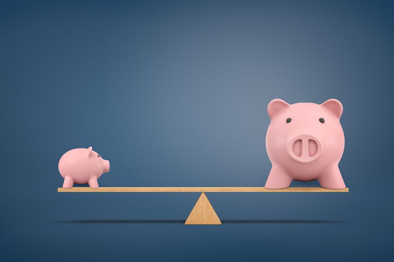 Smaller and larger piggy banks balanced on a lever