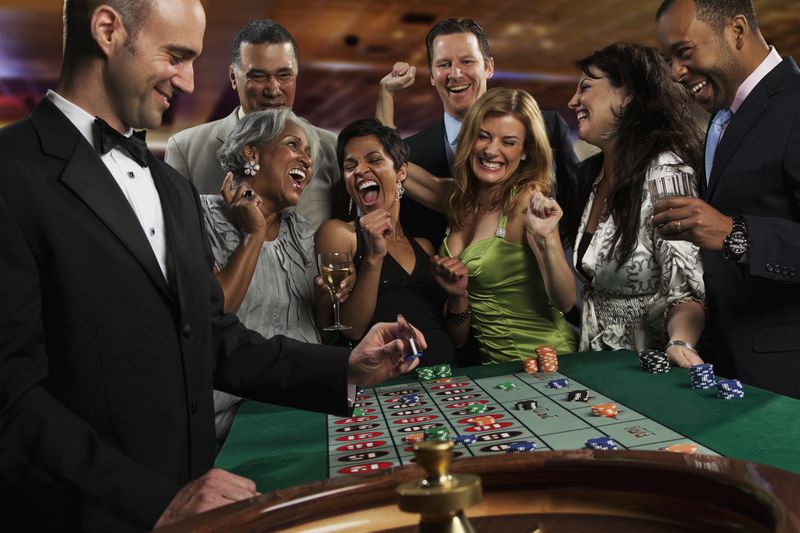 Excited friends gambling at roulette table in casino