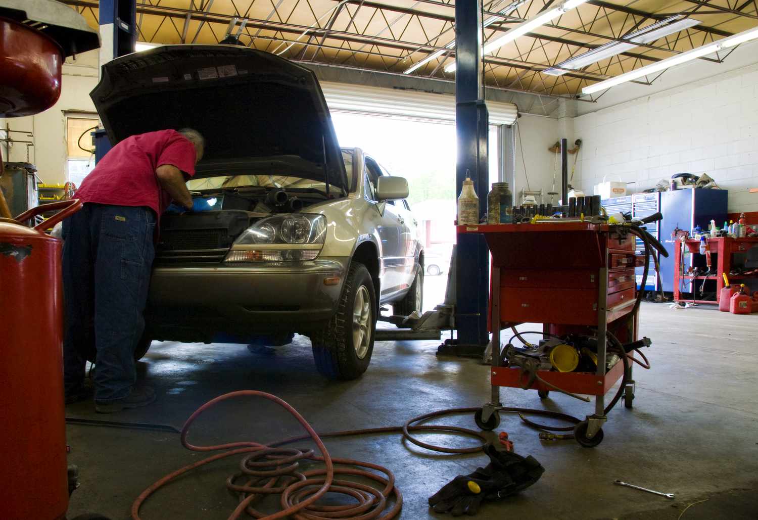 Mechanic working on car, leaning in under open hood